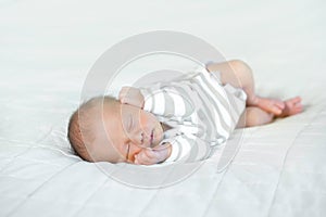 A beautiful sleeping newborn baby boy on a white blanket. He is