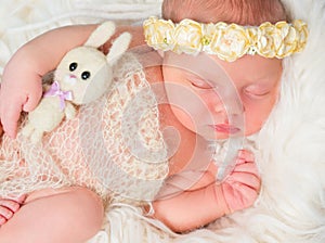 Beautiful sleeping newborn girl with toy and headband