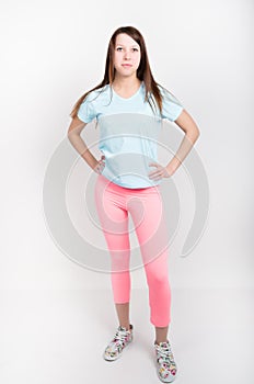 Beautiful slender athletic girl in pink leggings, a blue tank top and colorful Sneakers