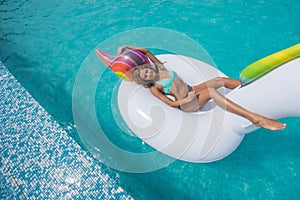 Beautiful slender blonde sitting big inflatable unicorn pool