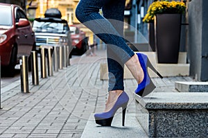 Beautiful slender female legs in tight jeans and blue velvet high-heeled shoes
