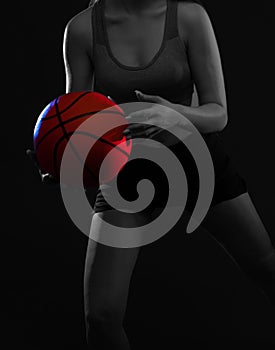 A beautiful slender girl athlete in shorts and a top plays basketball