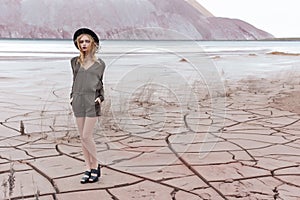 Beautiful slender girl in a black hat in the mountains with a strong wind