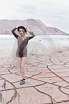 Beautiful slender girl in a black hat in the mountains with a strong wind