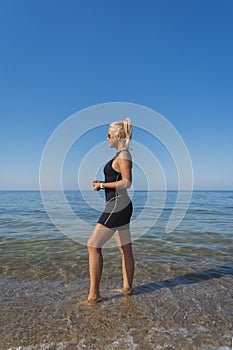 Beautiful slender girl in a neoprene swimming suit on the beach in Estonia in summer, vertical photo photo