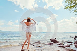 Beautiful slender girl relaxing on the rocky beach of a large lake