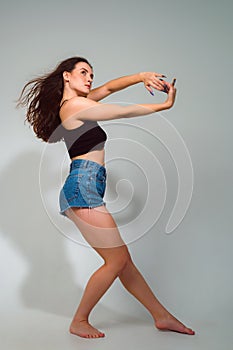 beautiful slender woman dancing in a photo studio. Dancehall dancer posing on gray background