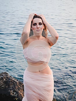 beautiful slender woman on the seashore posing in tulle. Dramatic makeup, wet hair