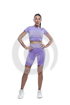 A beautiful slender young woman in purple sportswear is standing. Sports, beauty and active lifestyle. Full height. Isolated on a