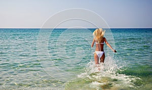 Beautiful slender young woman running in the sea waves