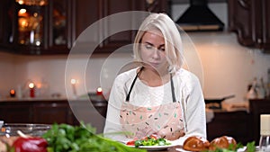 Beautiful slim Caucasian woman smelling tasty bun and eating healthful vegetarian salad. Portrait of upset young