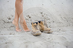 Beautiful, slim female legs in high leather boots. Girl with thick shoes on the sand