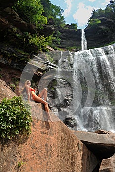 Beautiful slim fitness model posing in front of waterfalls