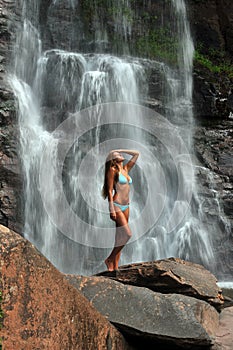 Beautiful slim fitness model posing in front of waterfalls