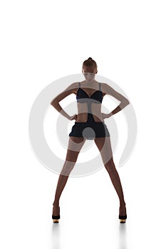 Beautiful slim go-go dancer in black dress with wide legs looking down