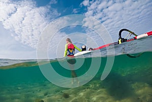 beautiful slim windsurfer girl walking along the sandy bottom