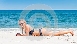 Beautiful slim woman in bikini lying on sand on the beach