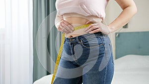 Beautiful slim woman measuring her waistline with yellow measuring tape. Concept of dieting, loosing weight and healthy