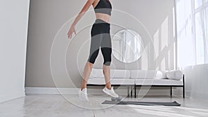 Beautiful slim woman in thirties with fair complexion does morning strenth and aerobic burpee exercises in modern airy