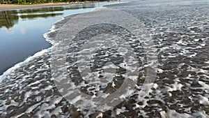 Beautiful slow motion footage of tidal wave on a sand beach with low tide and shallow water in the evening. Beauty of