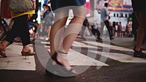 Beautiful slow motion shot of young female freelancer crossing a busy crowded street at night in Times Square, New York.