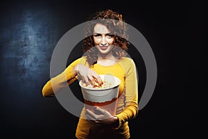 Beautiful sly woman grabs popcorn waiting for interesting movie