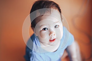 Beautiful small girl or boy with dark hair smiling on a bright orange background colour of 2019 with space for text happy smile