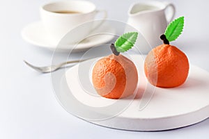 Beautiful Small Mousse Cake in Shape of Citrus Mandarin Tasty Modern Dessert Pastry White Blue Background Cup of Coffee