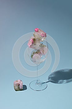 Beautiful small pink flowers in transparent glass on blue background with copy space. Sunny day concept