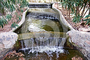 Beautiful small waterfall with cascades in Reina Sofia Park, Guardamar del Segura. Valencia, Spain.