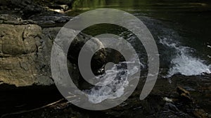 Beautiful small waterfall and giant stones. Creative. Cold mountainous river of a wild lake.