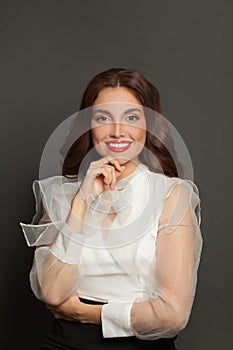 Beautiful smart smiling woman in white blouse on gray, studio portrait