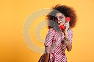 Beautiful smiling african woman in dress posing with retro phone