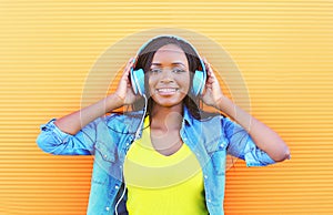 Beautiful smiling african woman with headphones enjoying listens to music