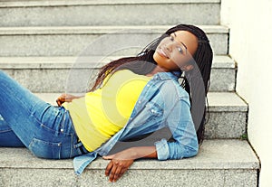 Beautiful smiling african woman wearing a jeans clothes on stairs
