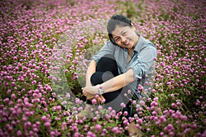 A beautiful smiling asian woman with hands on knee sits at garden park.