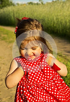 Beautiful smiling baby girl in red dress in summer day