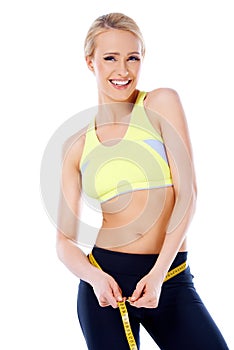 Beautiful smiling blond sporty woman measuring her waist