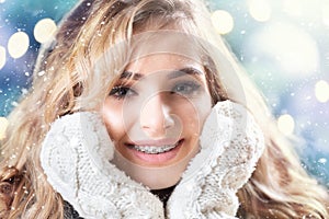 Beautiful smiling blonde with a dental braces during winter snowfall