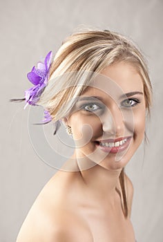 Beautiful smiling blonde girl with purple flower hair clip