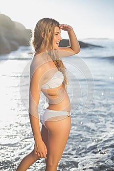 Beautiful smiling blonde looking out to sea at the beach