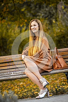 A beautiful and smiling blonde is sitting on a park bench
