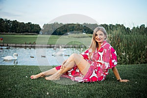 Beautiful smiling blonde woman lying on the grass outdoors. She is absolutely happy.