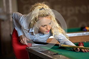 Beautiful smiling blonde women playing billiards