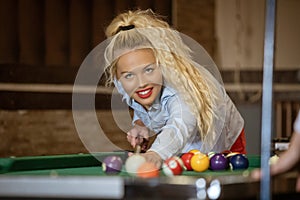 Beautiful smiling blonde women playing billiards