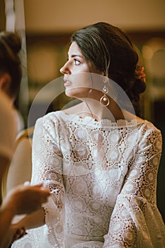 Beautiful smiling bride brunette young woman in white lace dress near window, bridal morning