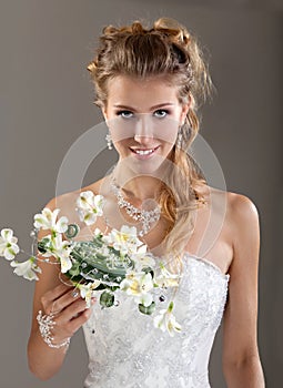 Beautiful smiling bride in the veil with bouquet. Gray Background