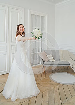 Beautiful smiling brunette woman bride in wedding dress with classical white roses bouquet, full length portrait