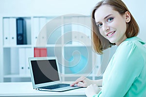 Beautiful smiling business woman sitting at office workplace half turn looking in camera portrait.