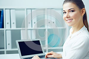 Beautiful smiling business woman sitting at office workplace half turn looking in camera portrait.